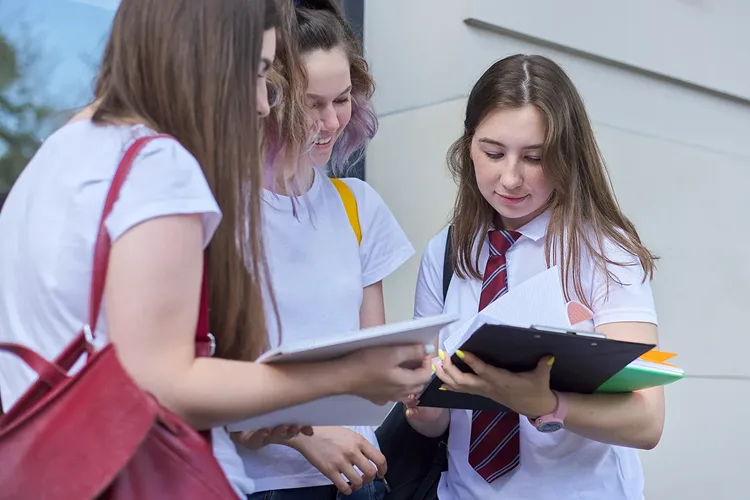 Three girls looking at notes outdoors