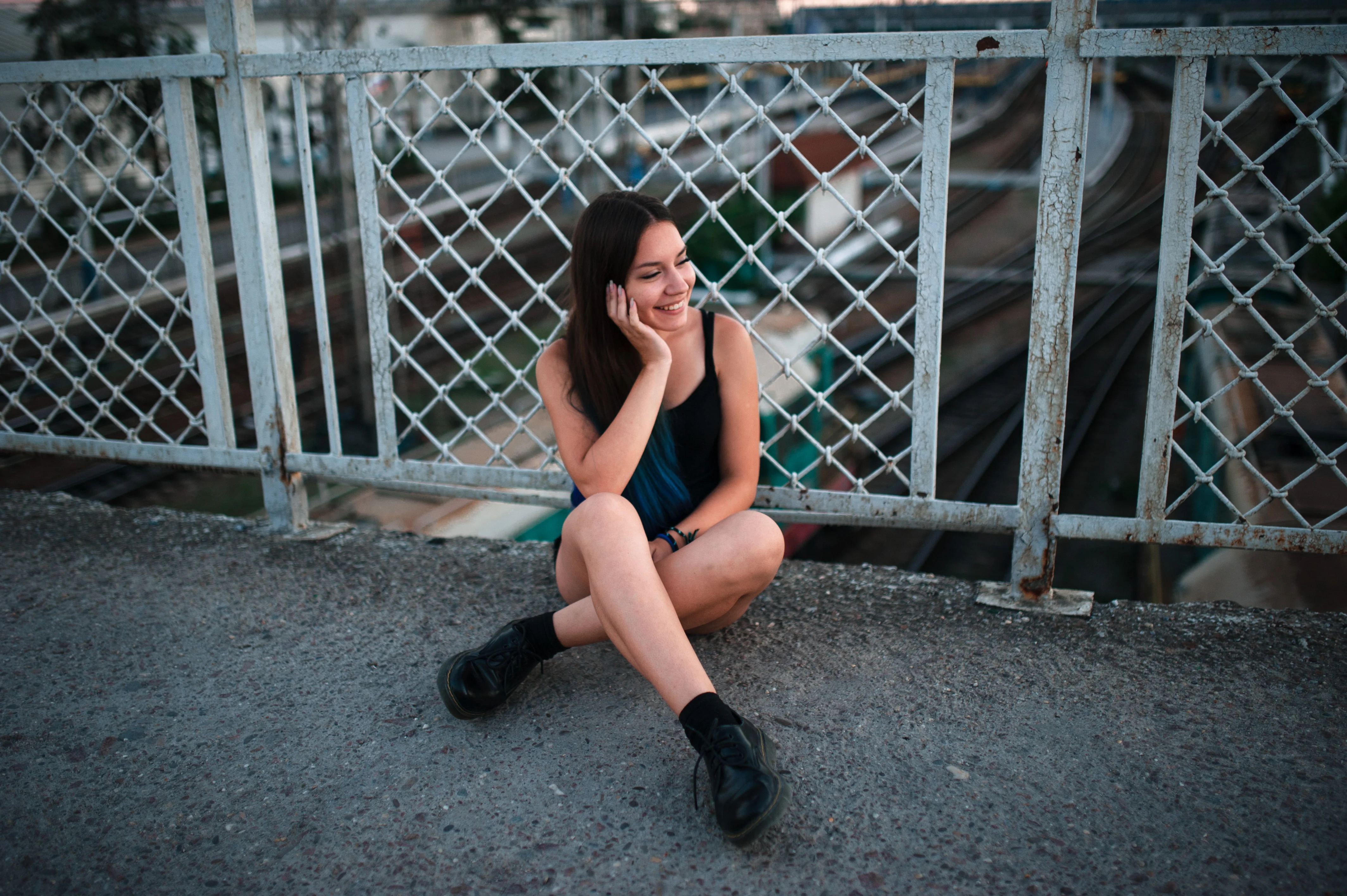 Girl sitting on a floor against a metal fence