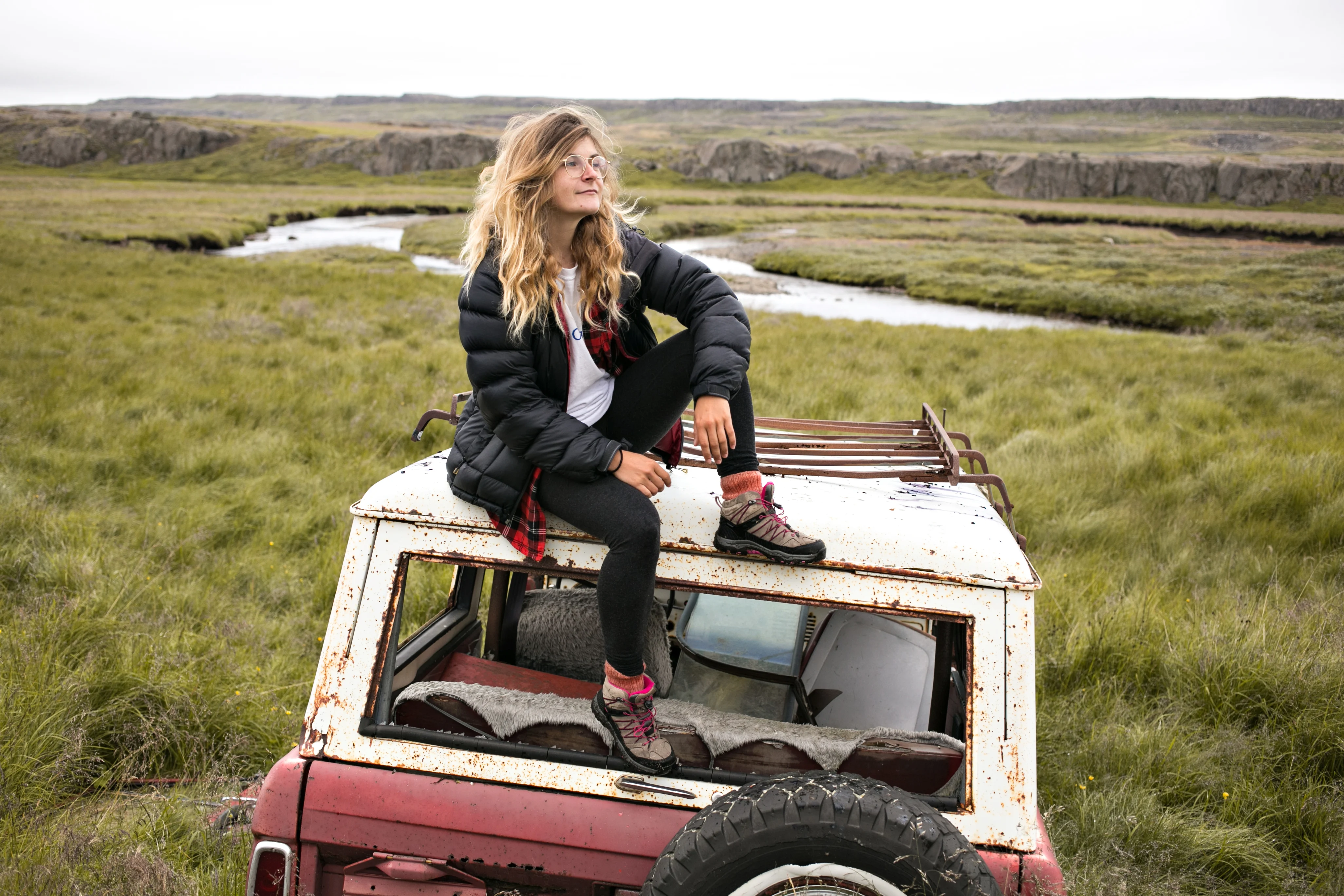 Woman sitting at the top of the car and looking at the distance