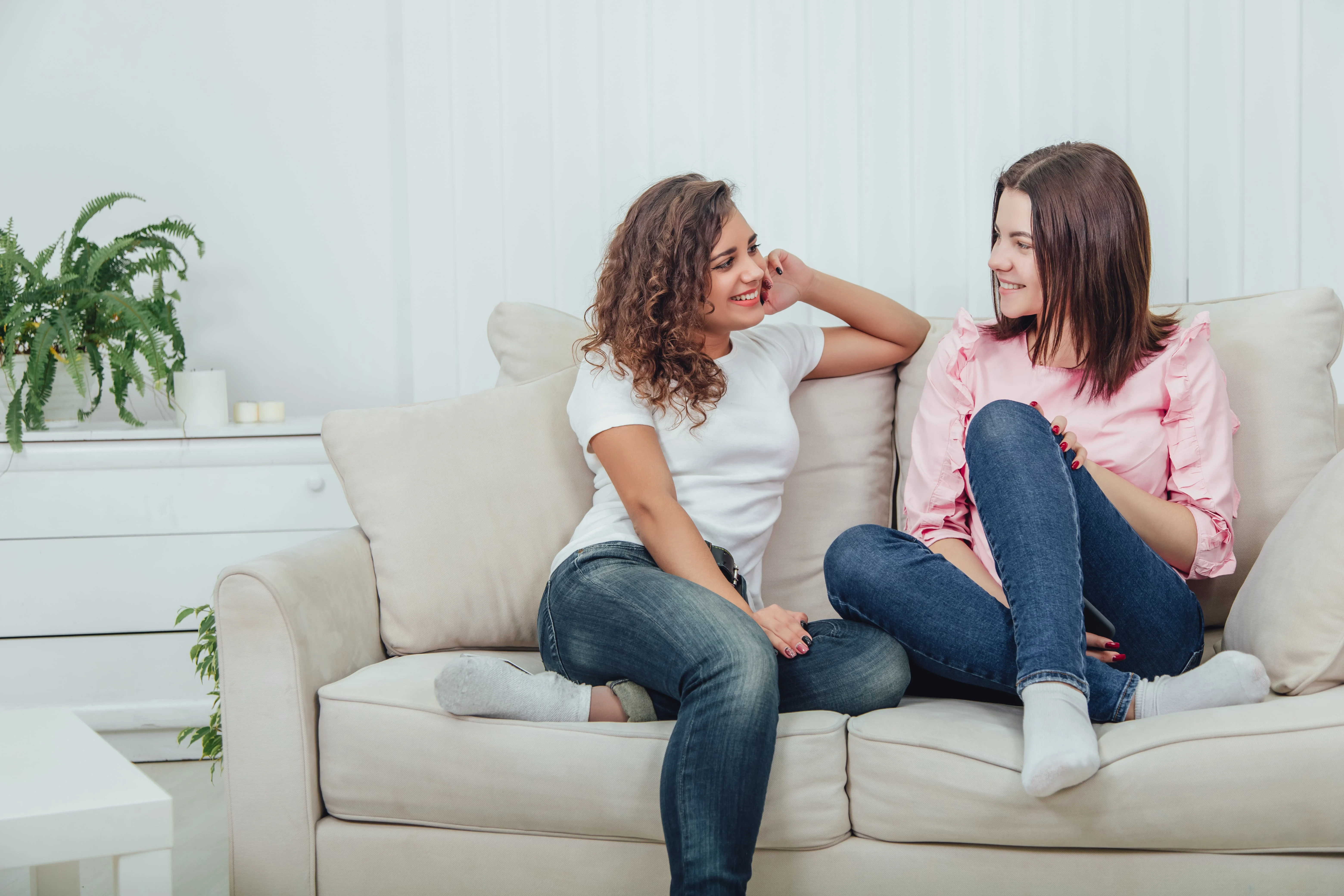 Two girls talking while sitting on a couch