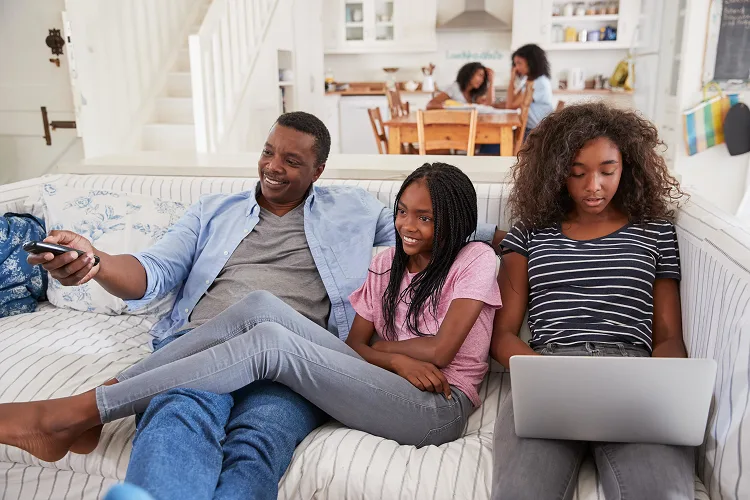 Dad and daughters watching TV from the couch