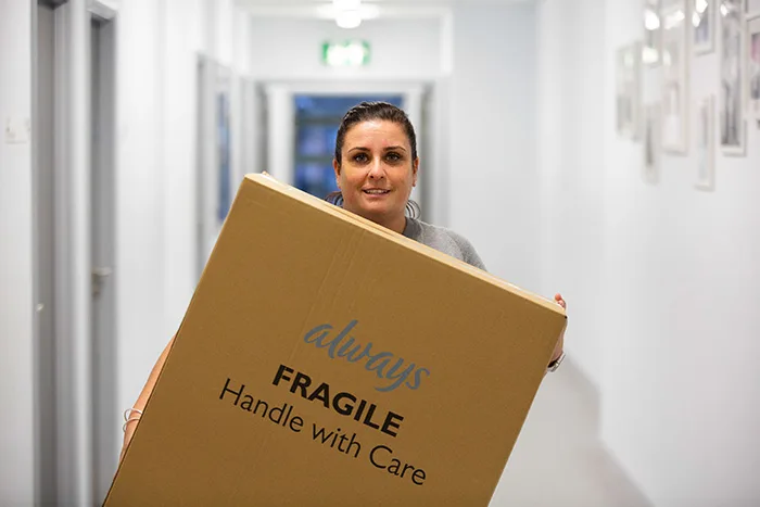 Woman carrying big cardboard box