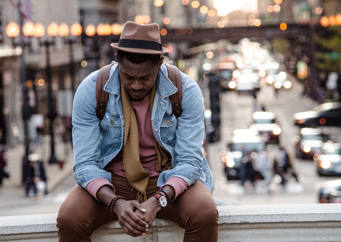 man-wearing-hat-sitting-on-ledge