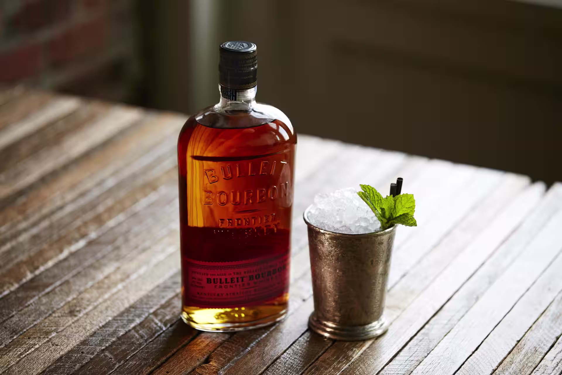 Mint Julep in a julep cup next to a bottle of Bulleit Bourbon