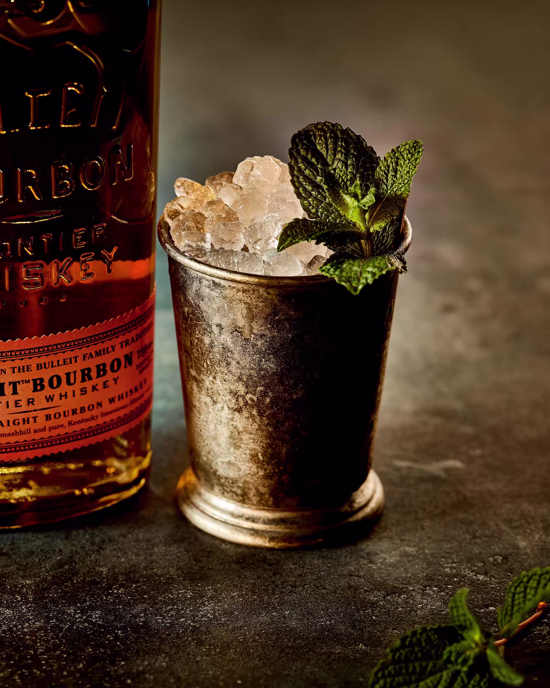 Mint Julep cocktail with crushed ice and fresh mint beside a Bulleit Bourbon bottle
