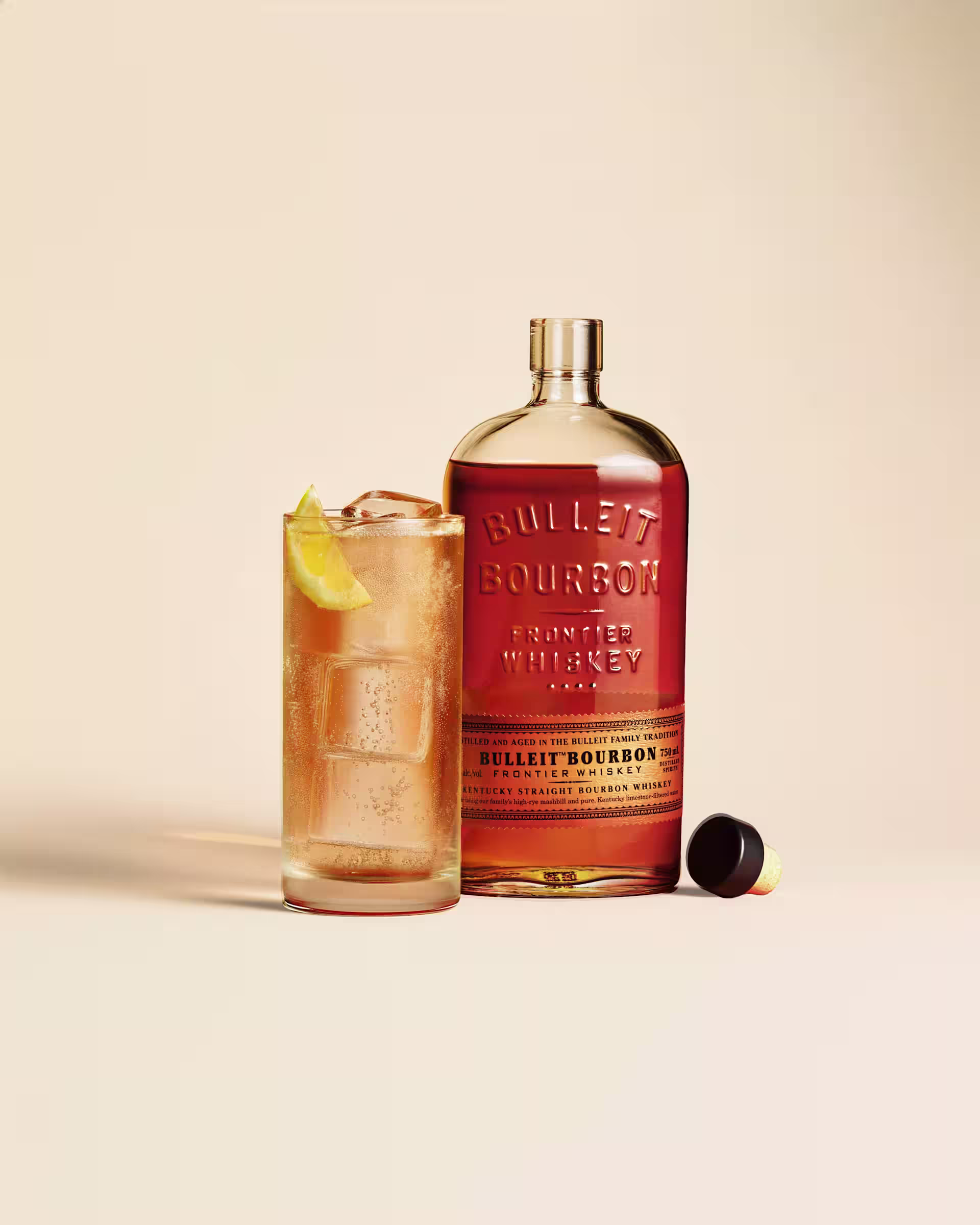BLT cocktail with ice and lemon garnish beside a Bulleit Bourbon whiskey bottle
