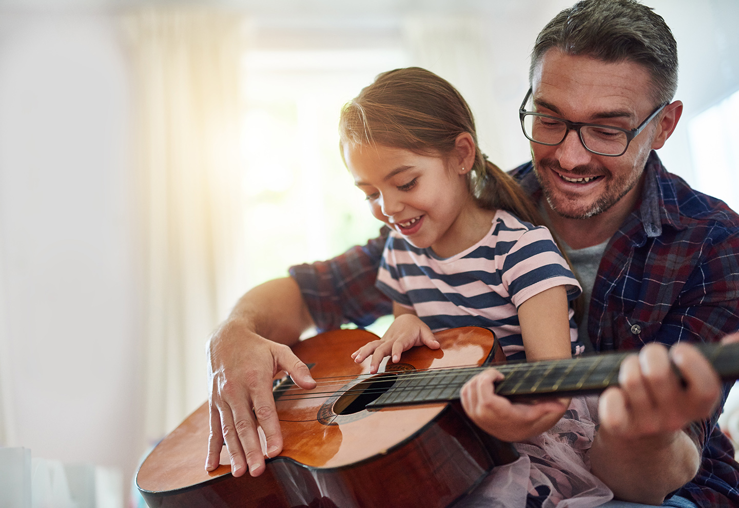 Father playing the guitar with his young daughter