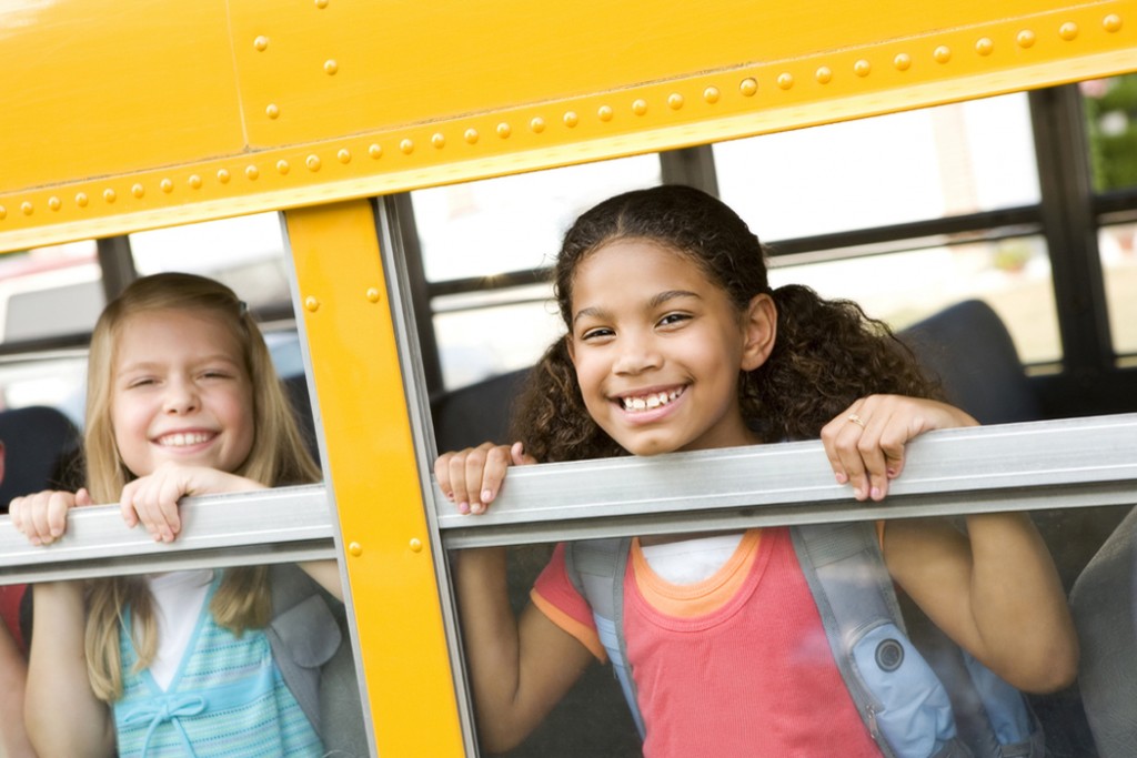 Kids looking out of a school bus window