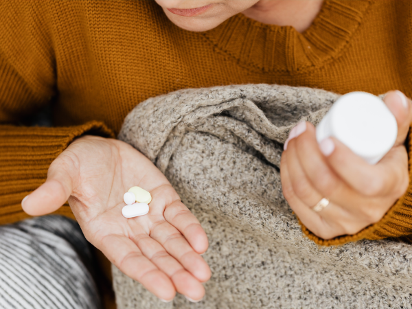 Hands holding medication bottle and white pills