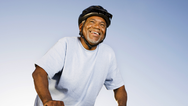 Middle-aged man riding a bicycle while wearing a helmet and smiling
