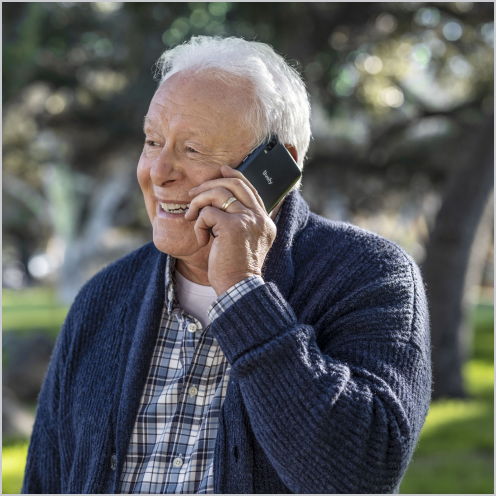 News - Older man walking outside while speaking on his smart phone