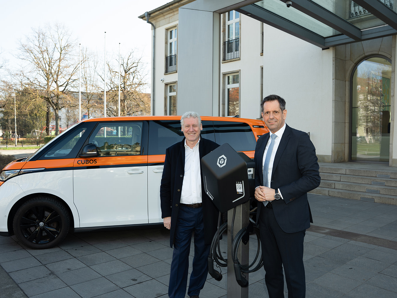 Marc Will von CUBOS mit Olaf Lies, Ministerpräsident von Niedersachsen, stehen vor der Niedersächsischen Staatskanzlei und begrüßen den Landesauftrag von CUBOS im Land Niedersachsen