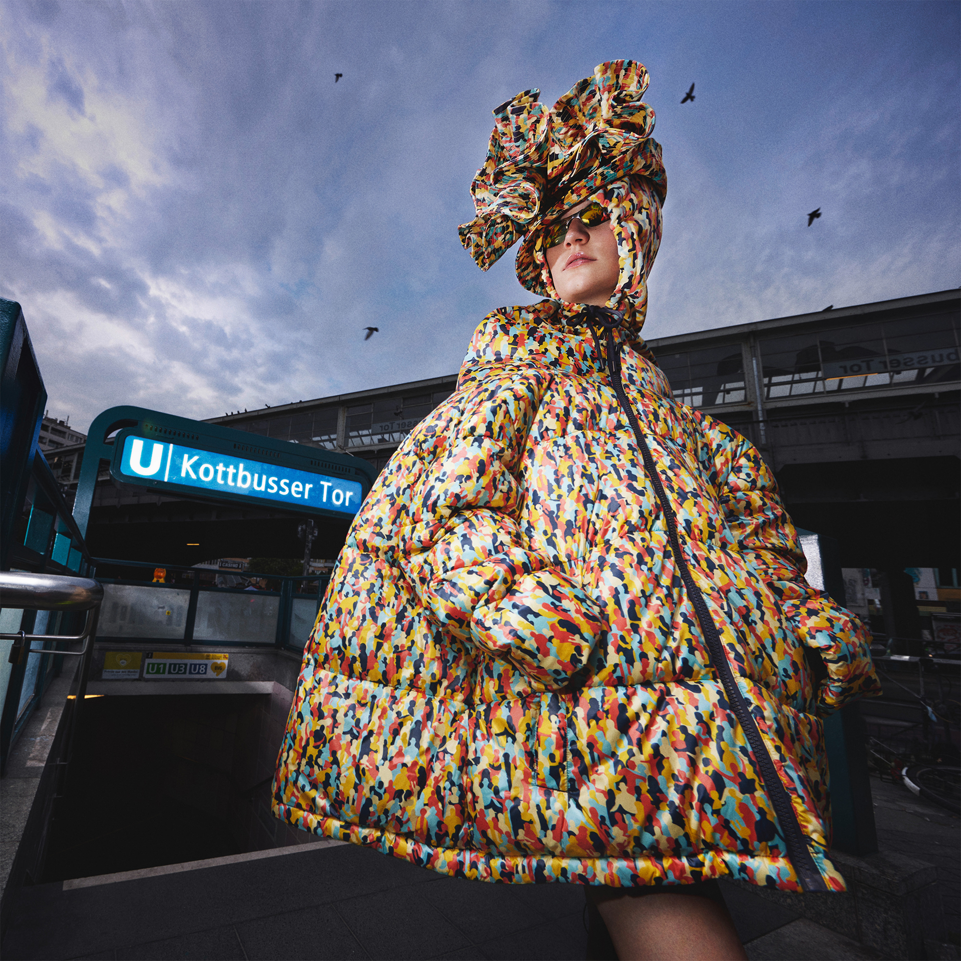 A woman stands in front of the train station kottbusser tor and wears an oversized jacket in the so-called Pattern of Tolerance of Jung von Matt’s Campaign for BVG, Berlin’s public transport company.