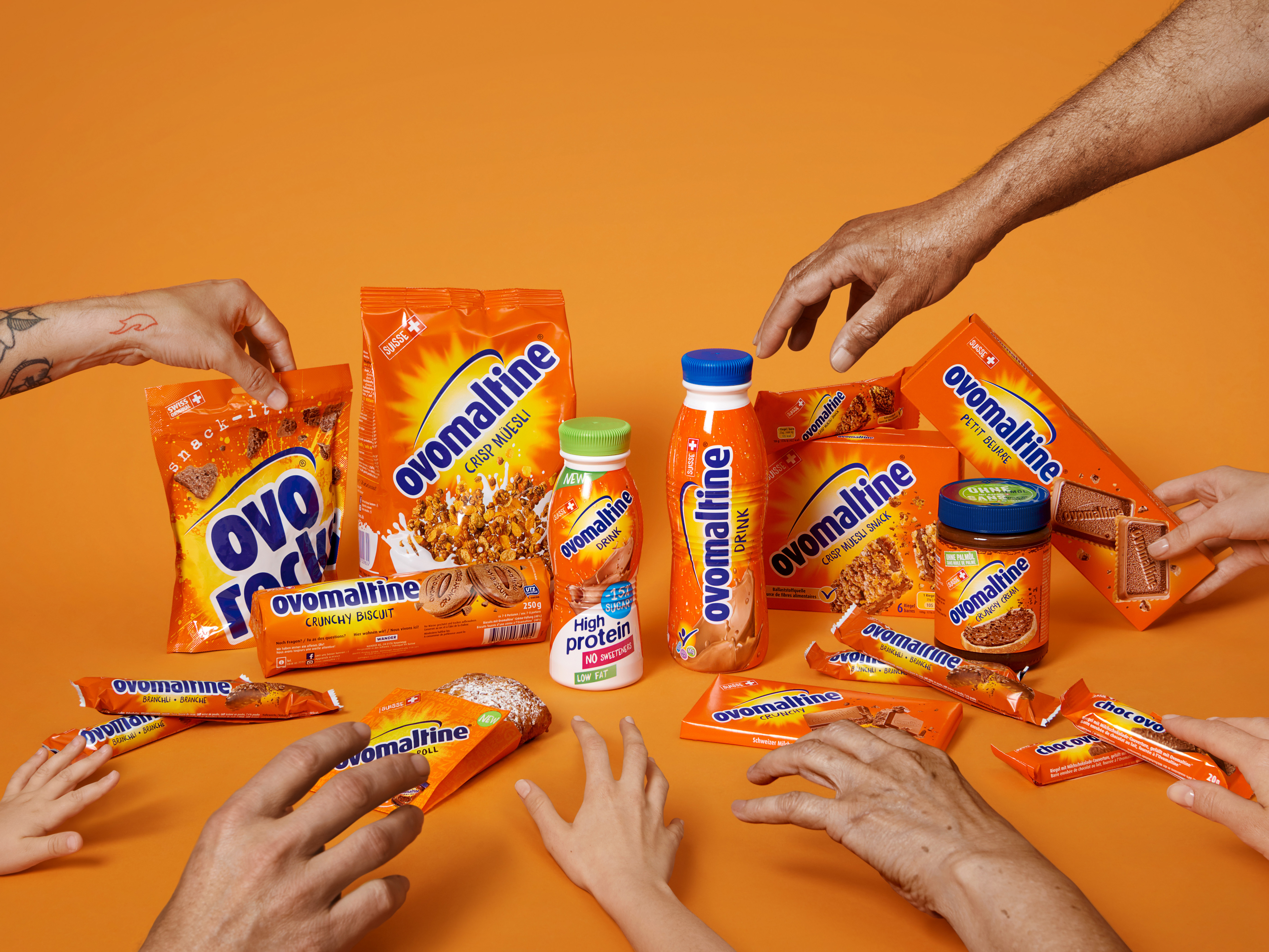 Pictures of a product image from BLISH for Ovomaltine. Hands are reaching for the different products in front of an orange background.