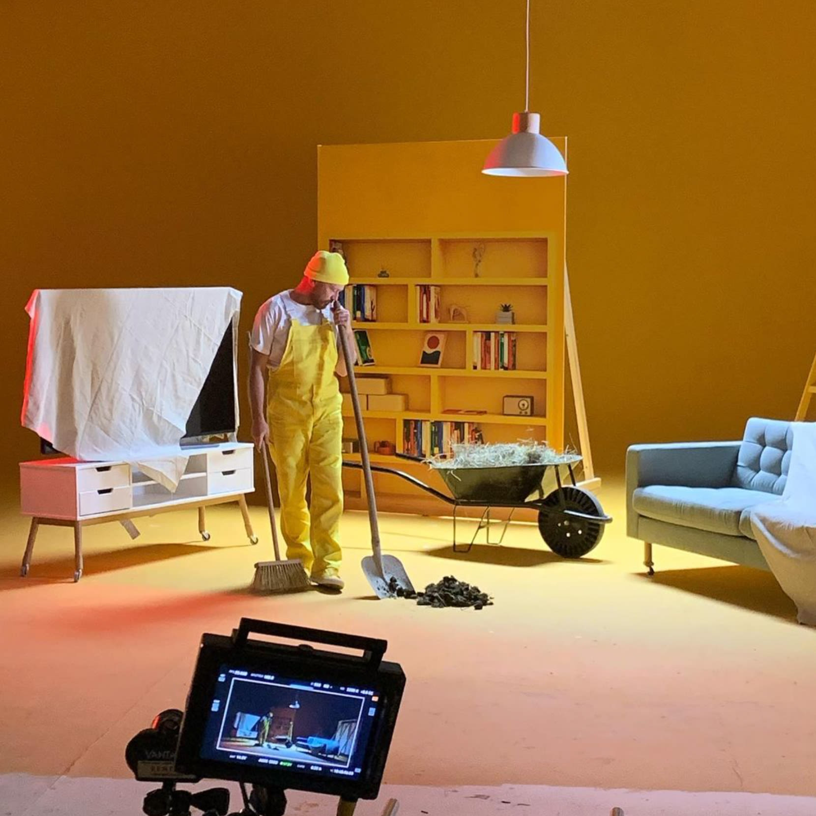  A man in bright yellow overalls is busy cleaning a room, making it look fresh and tidy.  