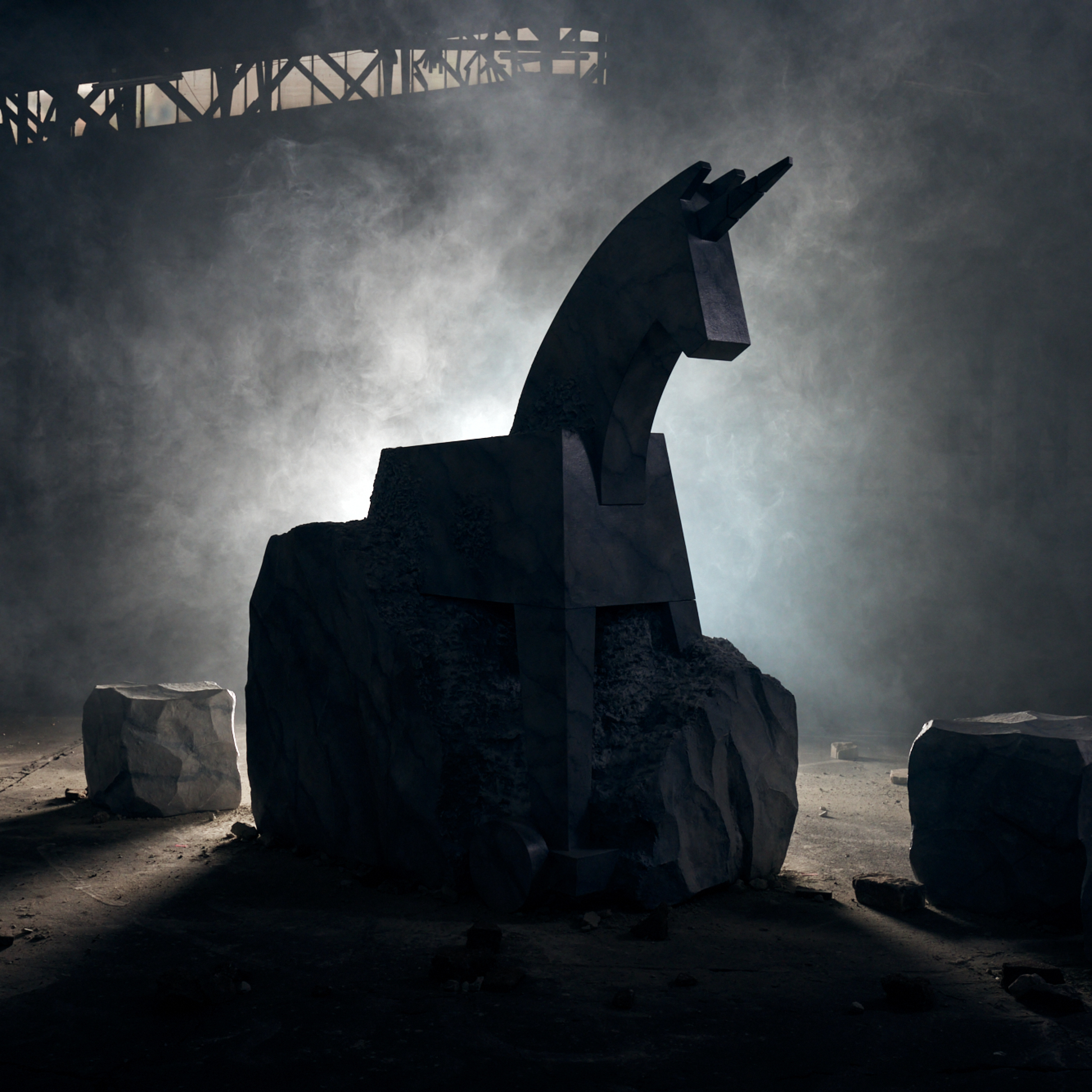 Image showing a sculpture of a Trojan horse, Jung von Matt's brand logo, emerging from a stone-like rock in the middle of a dark room.