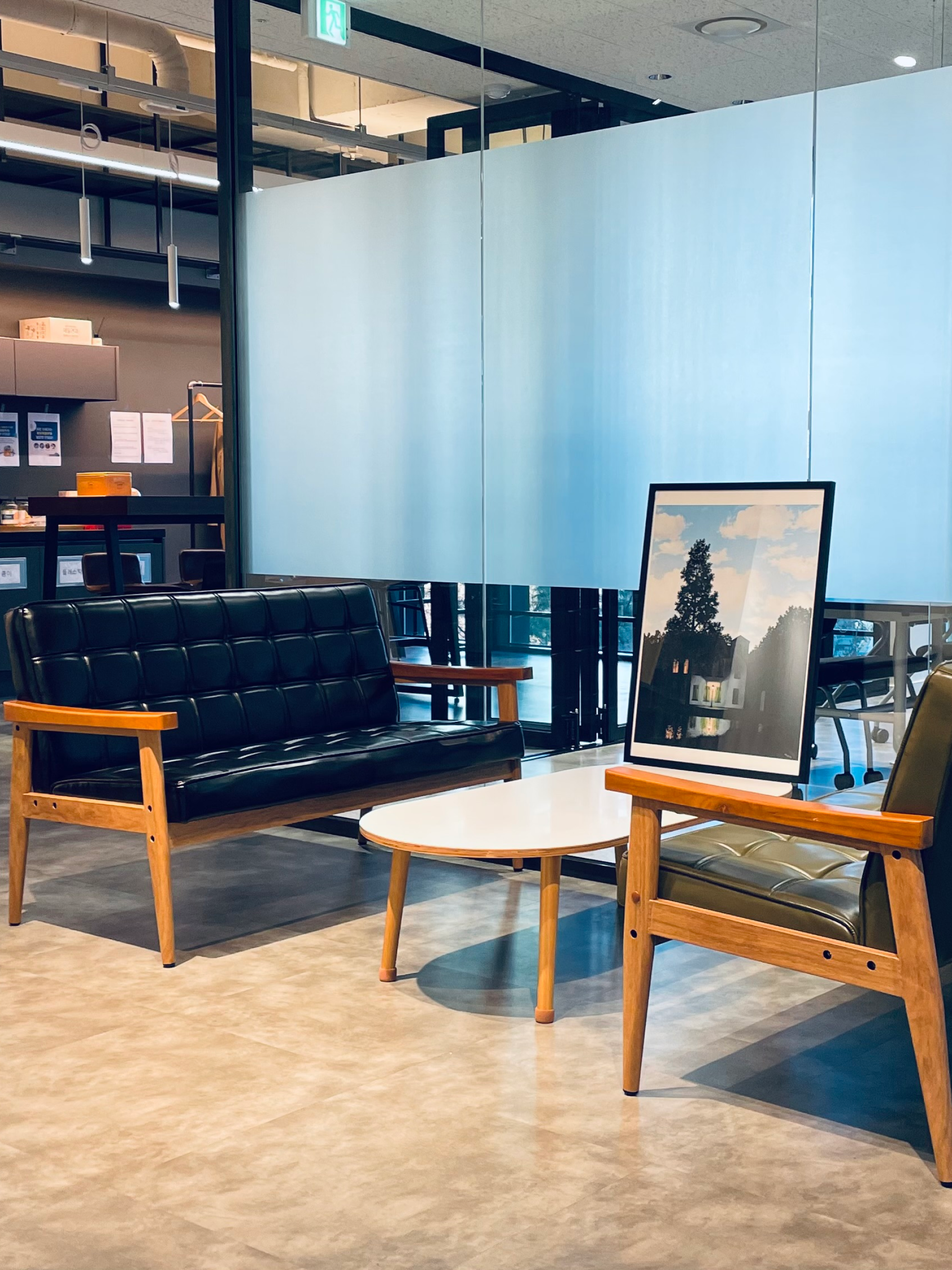 Picture from the inside of the Jung von Matt office building HANGKANG in Seoul. You can see two benches facing each other with a table in the middle. On the table is a picture of a house.