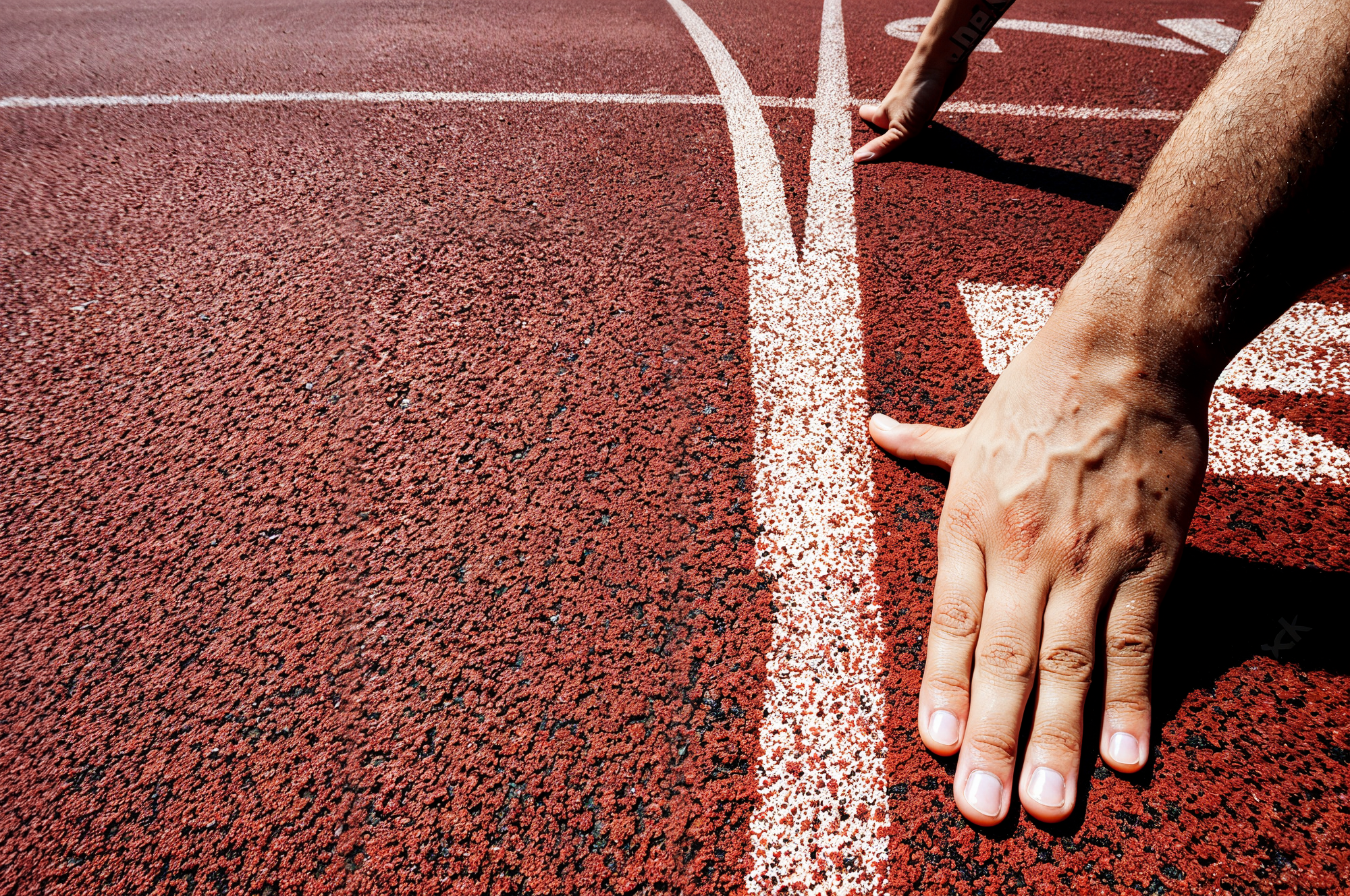 Image of a runner in starting position on a running track. 