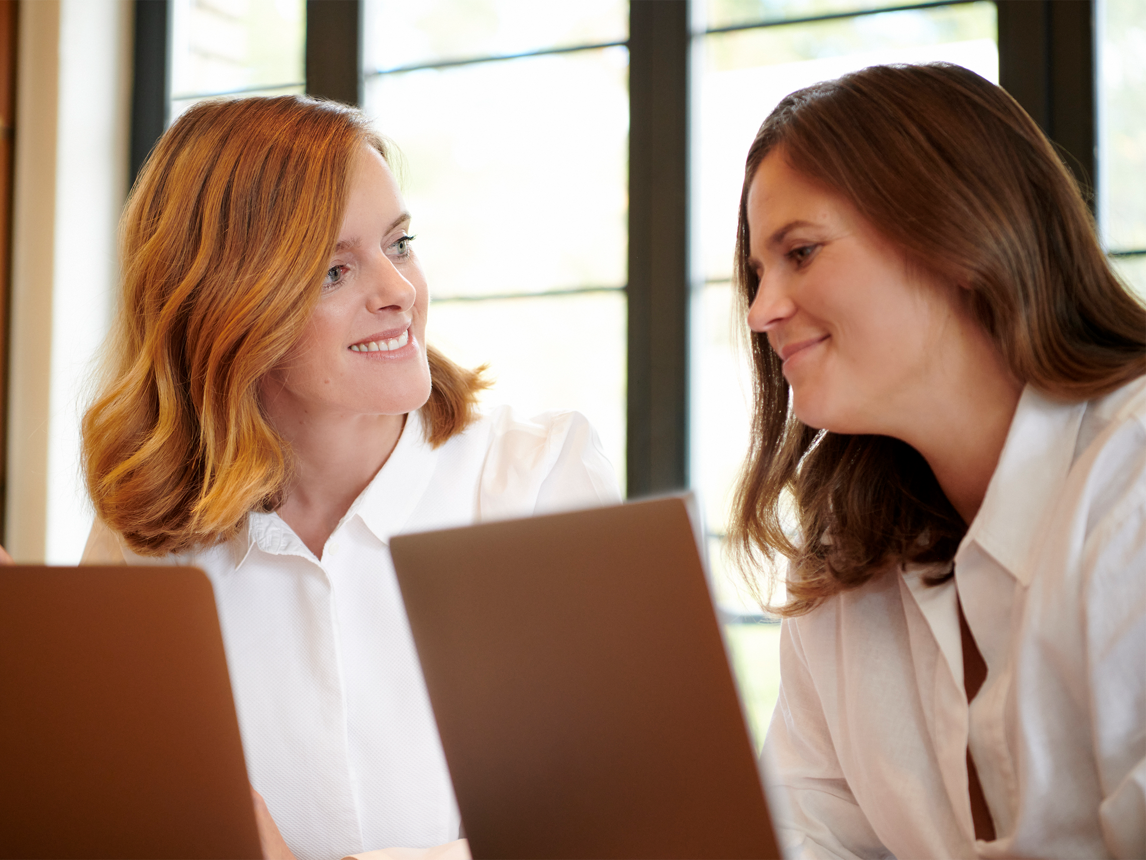 Photo of Nathalie Eggen and Yvonne Samaritani, managing directors of JUNE Corporate Communications, working on two laptops.