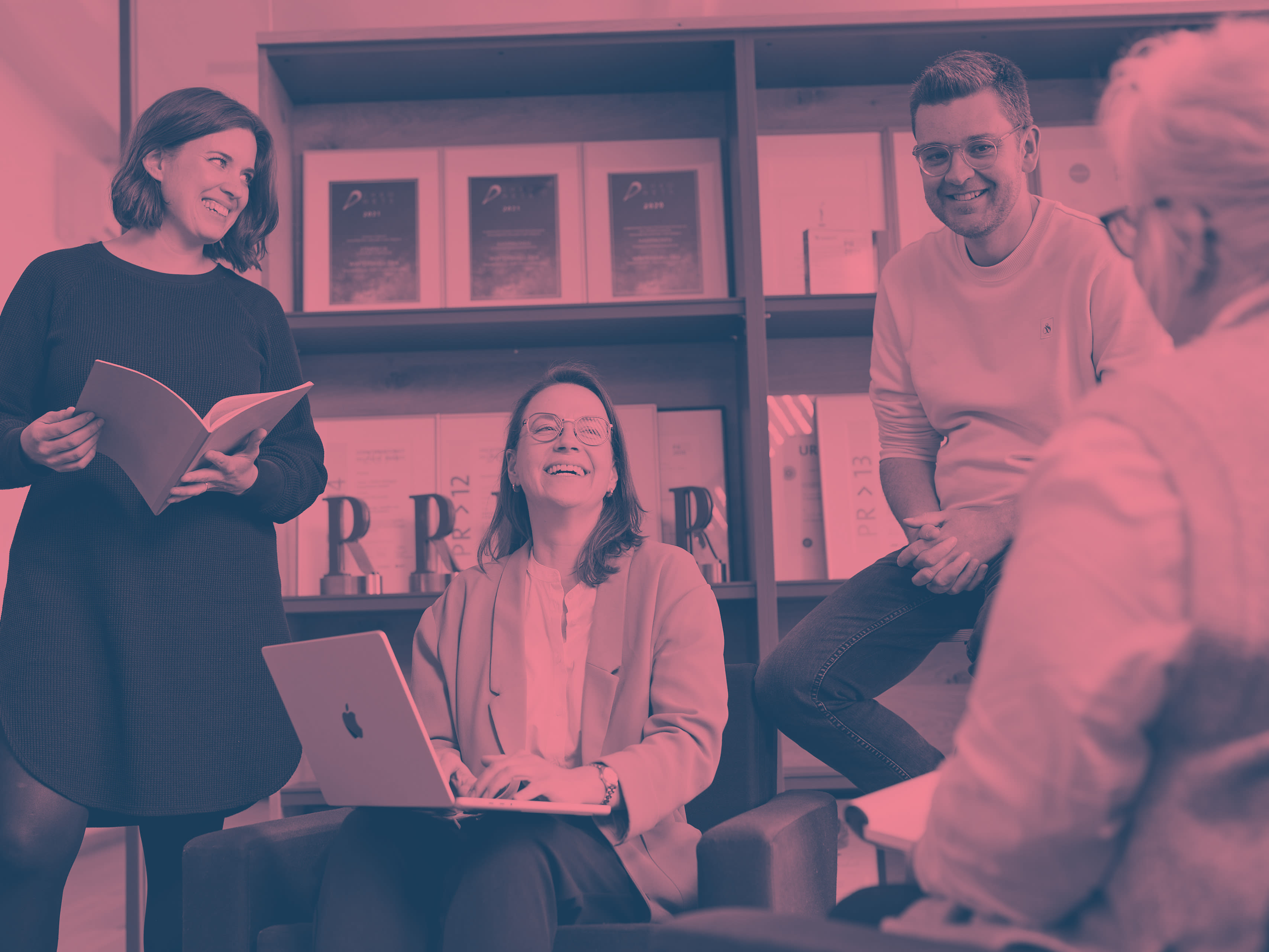 Slightly red colored image of four smiling navos employees who seem to be talking to each other.