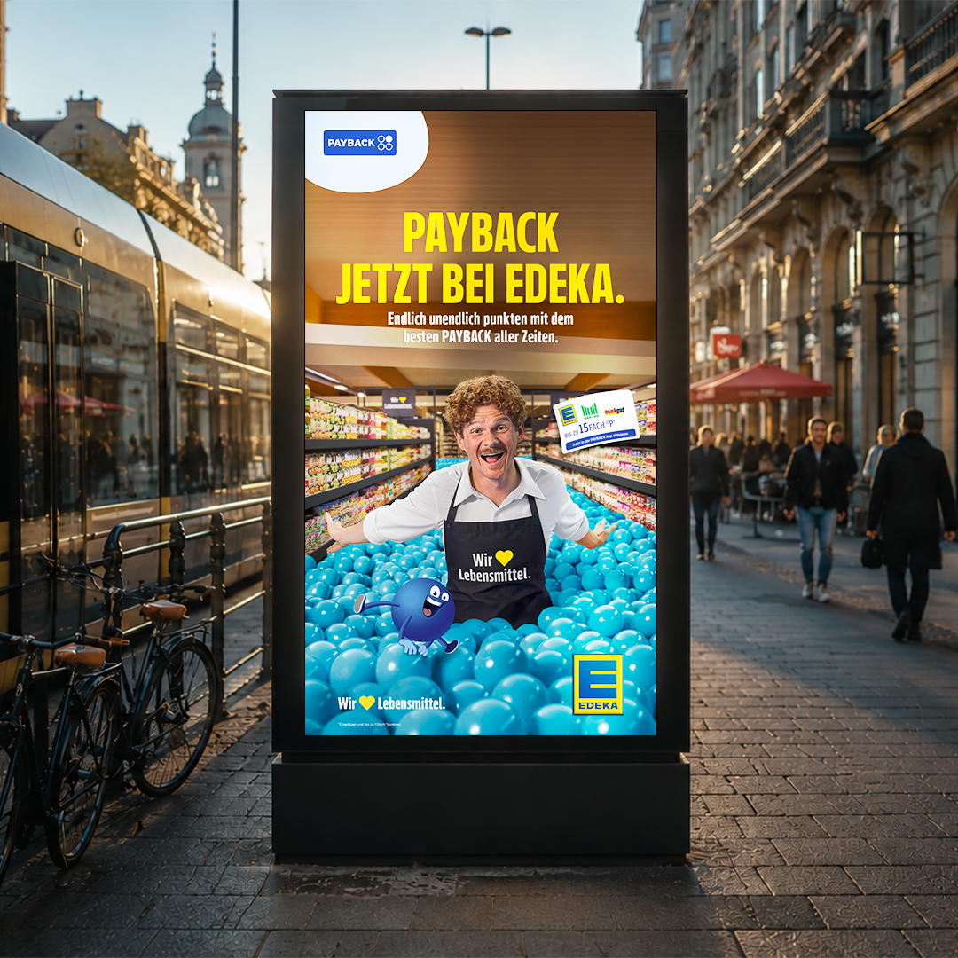 A bus shelter advertisement displays a smiling man in a light blue shirt and white apron, surrounded by blue balloons. The ad promotes PAYBACK at EDEKA, featuring the slogan "PAYBACK JETZT BEI EDEKA" in large text.