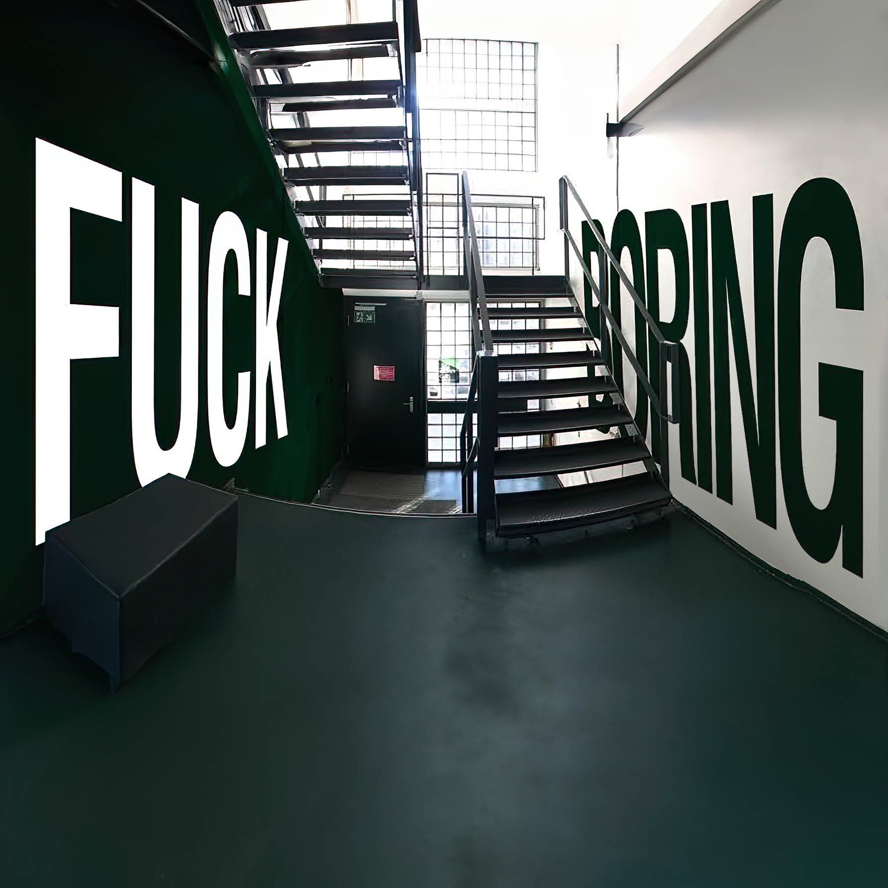 Image of a staircase at the Jung von Matt location in Hamburg, on the walls on the left and right the motto lettering in "FUCK BORING" in black and white.