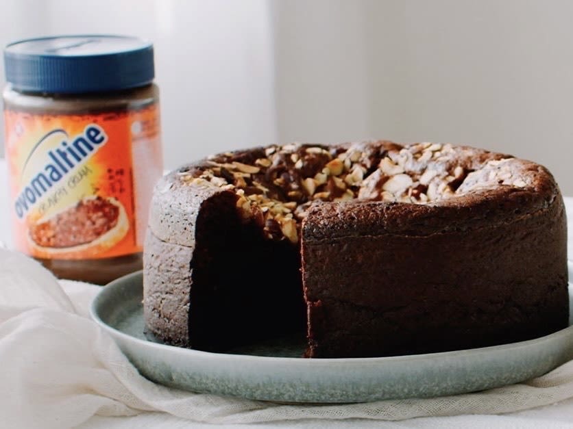 Image of a brown round cake from a campaign by Jung von Matt IMPACT Zurich for Ovomaltine. In the background is a blurred glass of Ovomaltine.