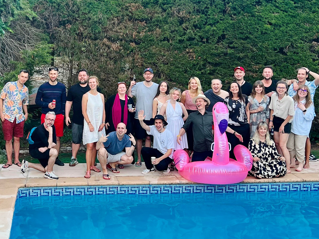 Group of people posing near pool, happy and relaxed.