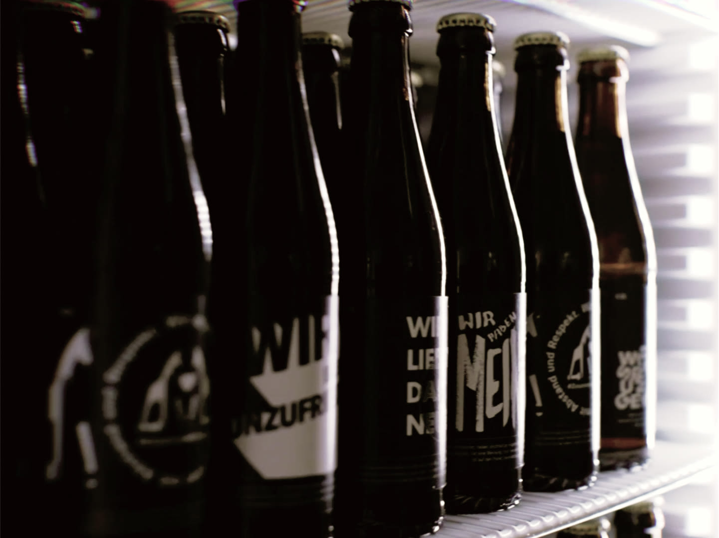 Image of various glass beer bottles in different Jung by Matt TECH looks in a refrigerator.