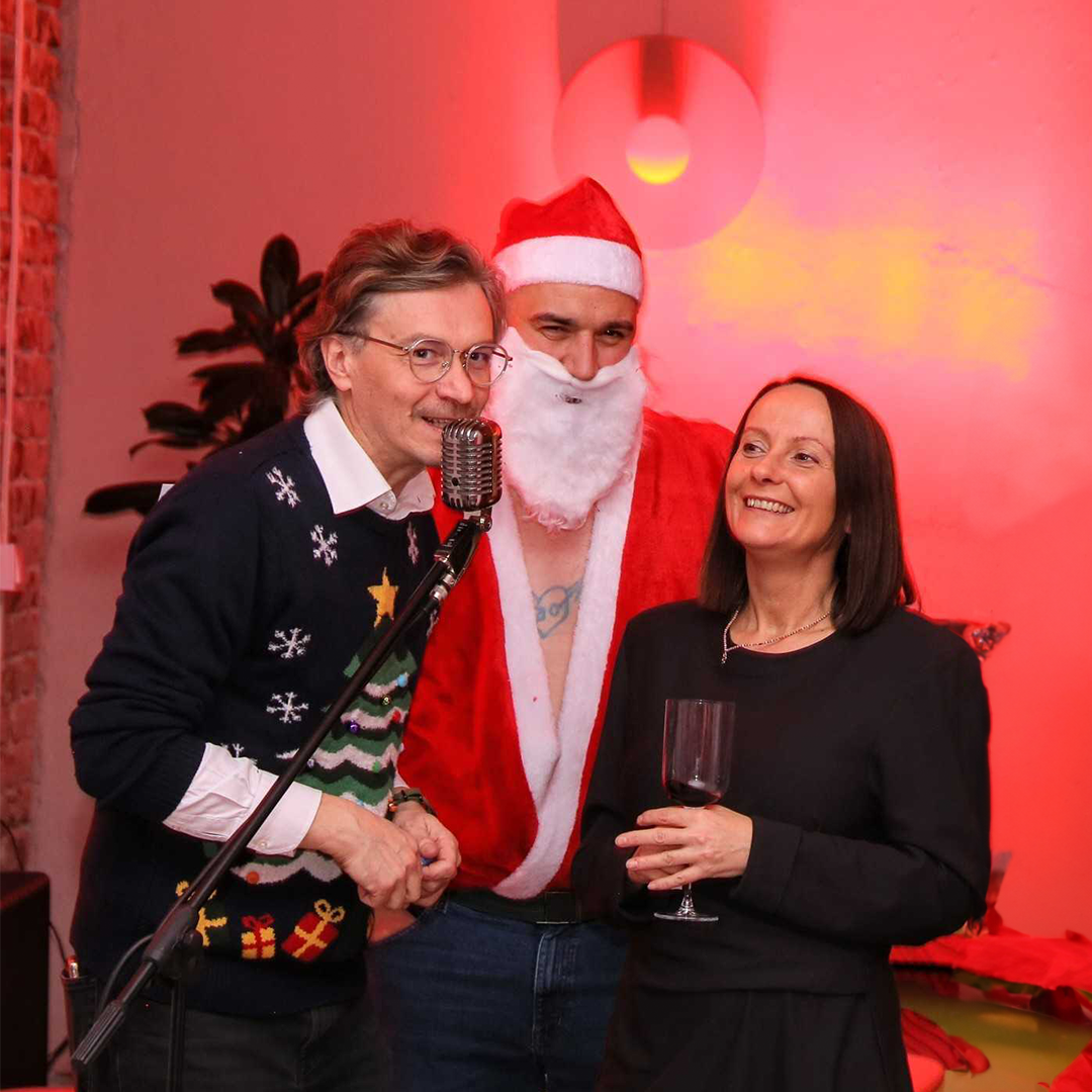 A man and woman posing with a man in a Santa suit.