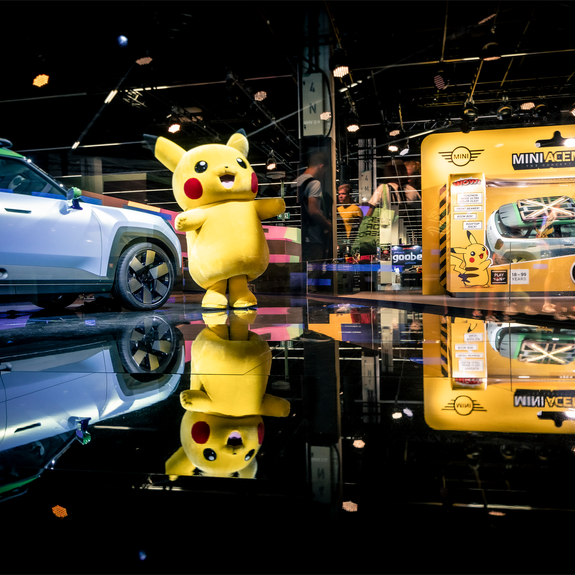 Picture of a Pikachu mascot next to the concept car Aceman in life-sized toy packaging, which was created from the collboration of pokémon and MINI, at the gamescom 2022.