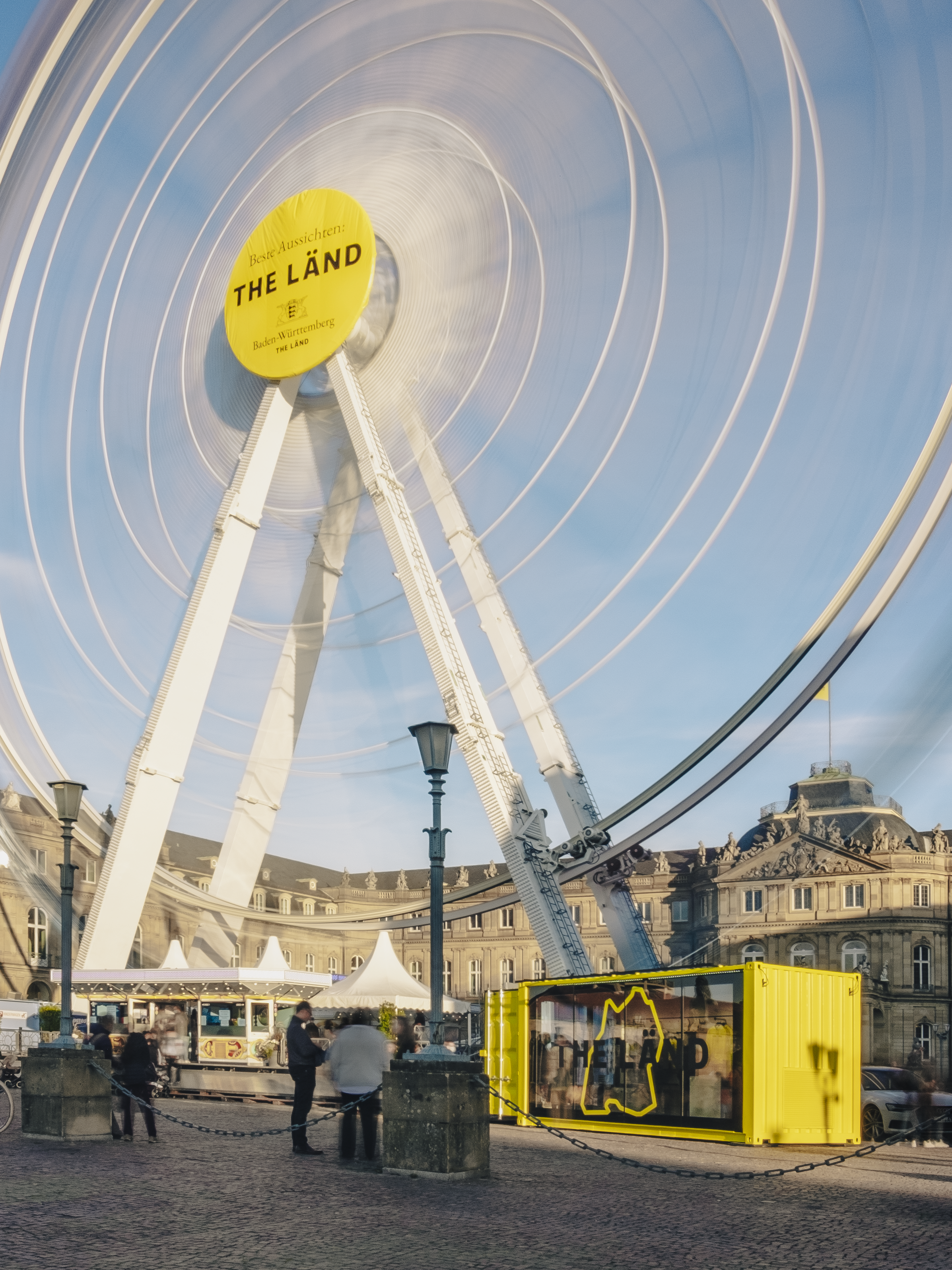 A vibrant land ferris wheel stands tall against a clear blue sky, inviting visitors for a fun ride and stunning views.