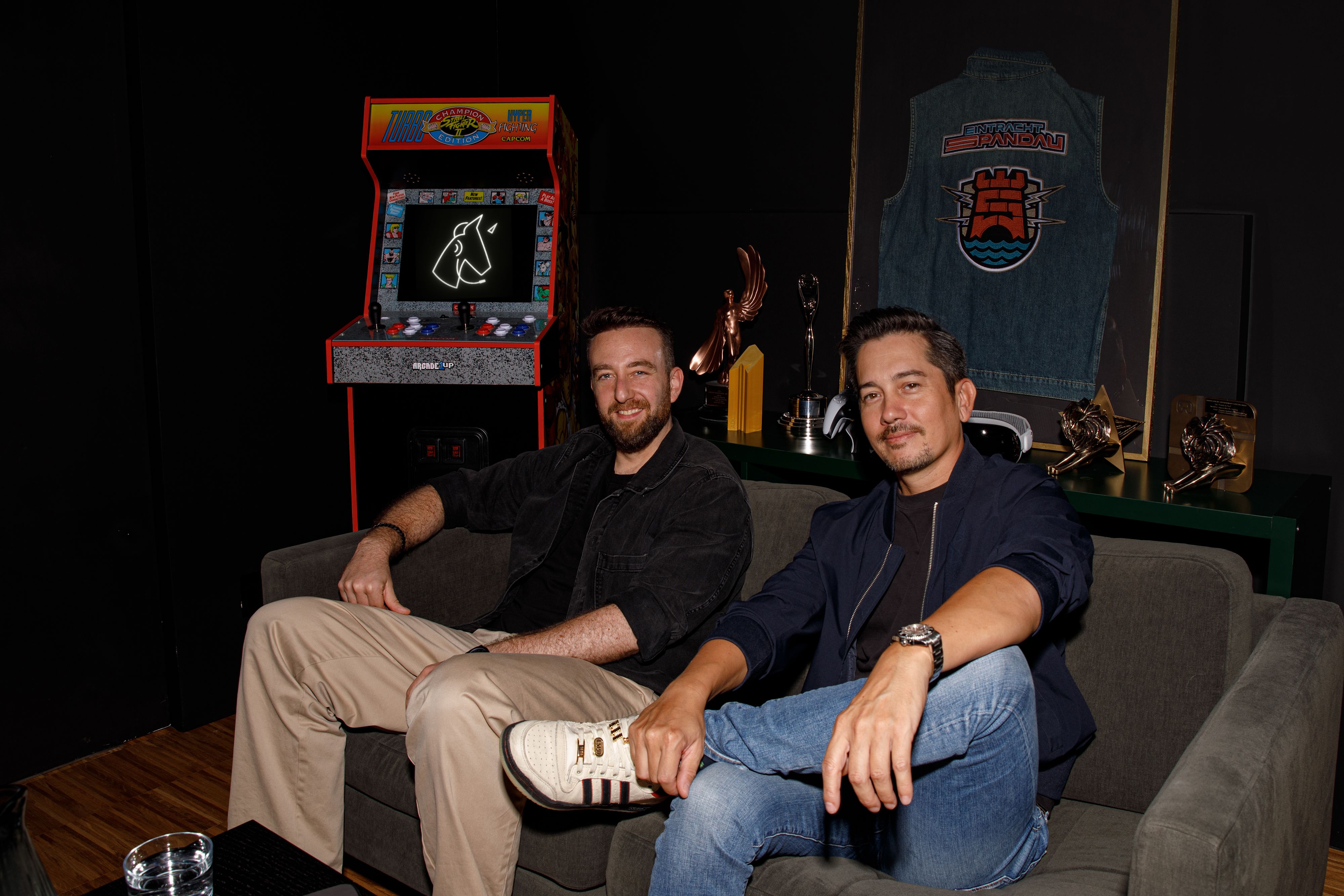 Picture of the managing directors of Jung von Matt NERD, André Price and Toan Nguyen, lying on the floor between toys and holding two Nerf pistols.