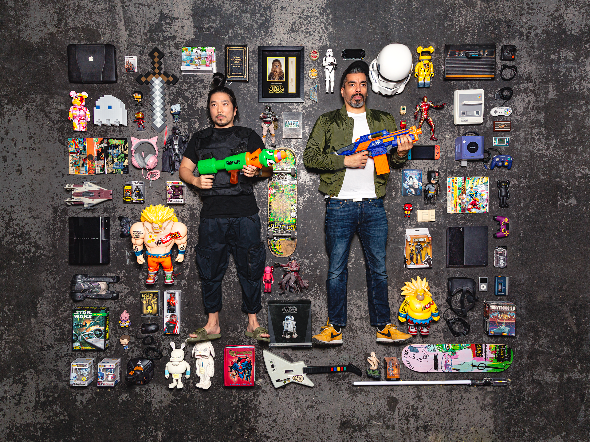 Picture of the managing directors of Jung von Matt NERD, André Price and Toan Nguyen, lying on the floor between toys and holding two Nerf pistols.