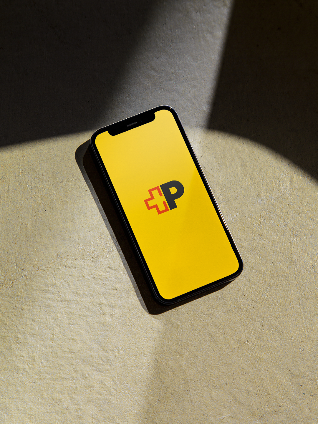 Image from the brand strategy campaign by Jung von Matt BRAND IDENTITY for the Swiss Post. The image shows a smartphone with the new brand logo consisting of a stylized red Swiss cross and a black "P" on a postal yellow background.