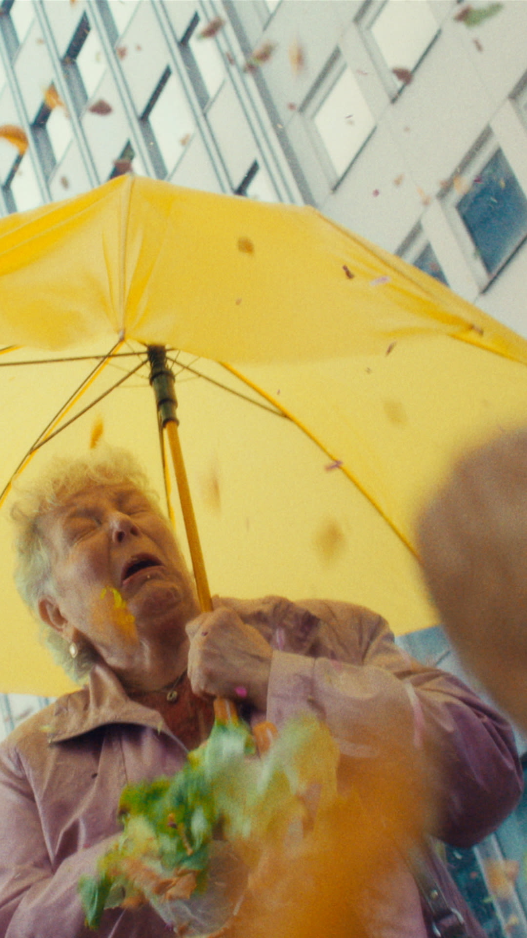  A woman stands under a bright yellow umbrella, adding a pop of color to a rainy day.  