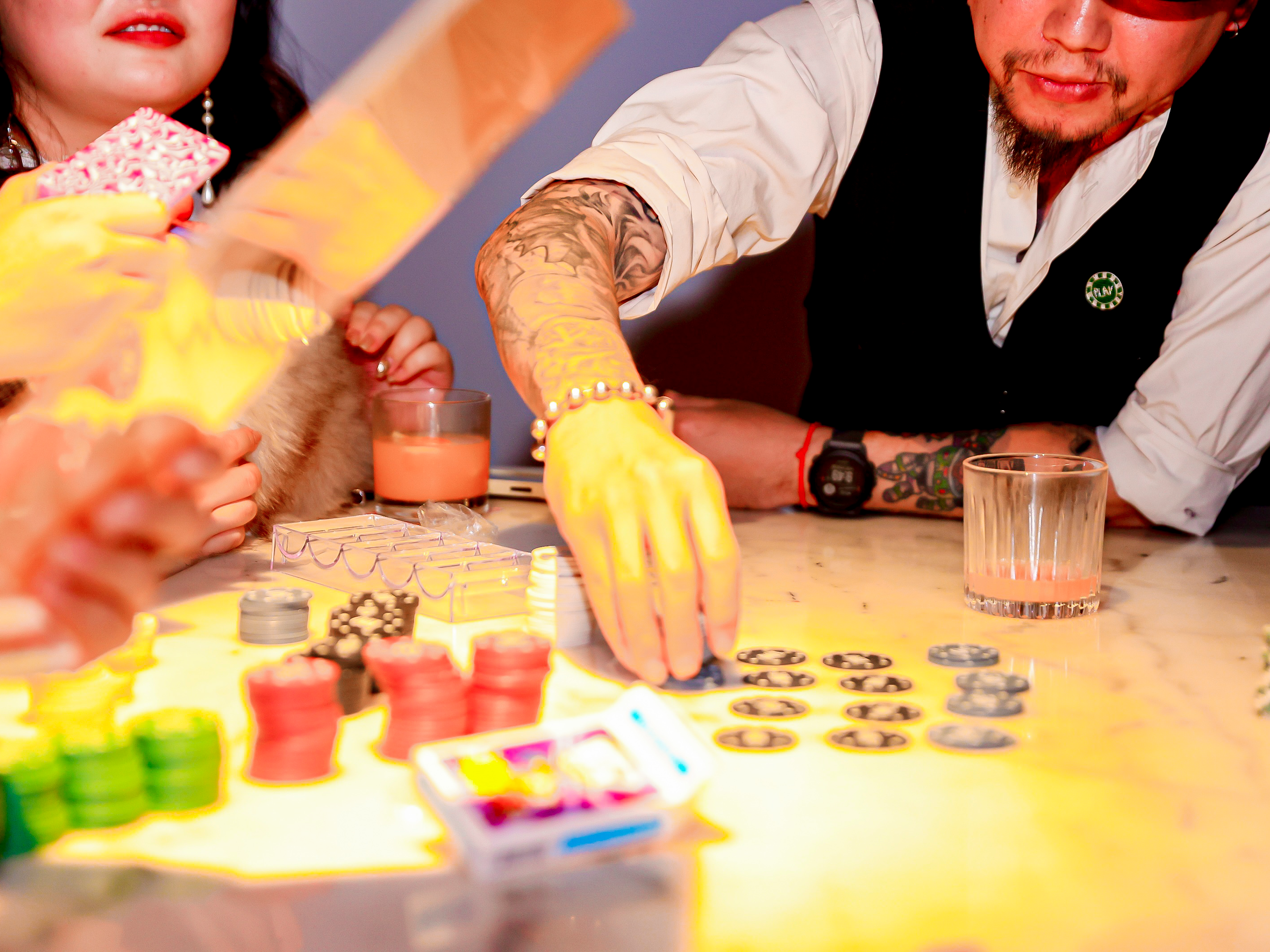 Picture of a group of people sitting around a table playing poker-like games with colorful chips.