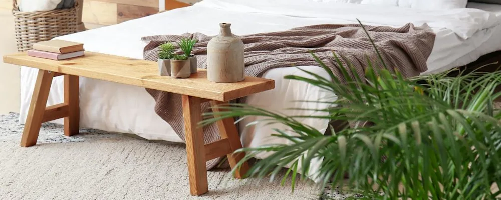 A cosy bedroom using a bench as a storage place at the foot end