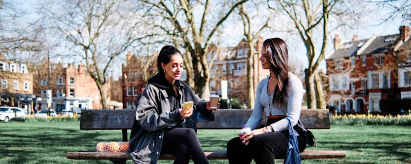 Two college girls sitting on a bench and discussing self storage