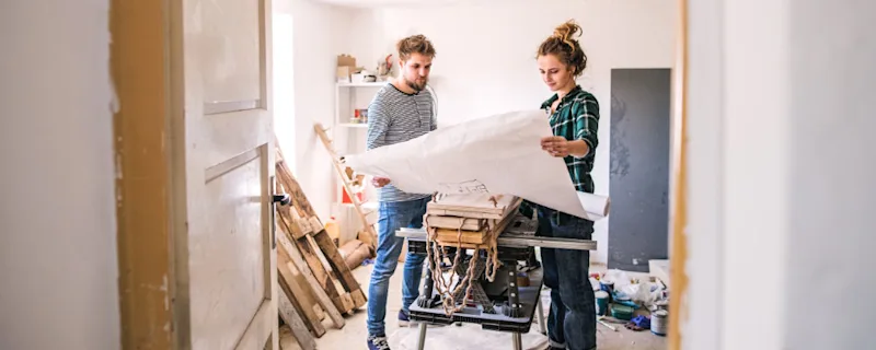 A couple looking at a floorplan while doing home renovations.