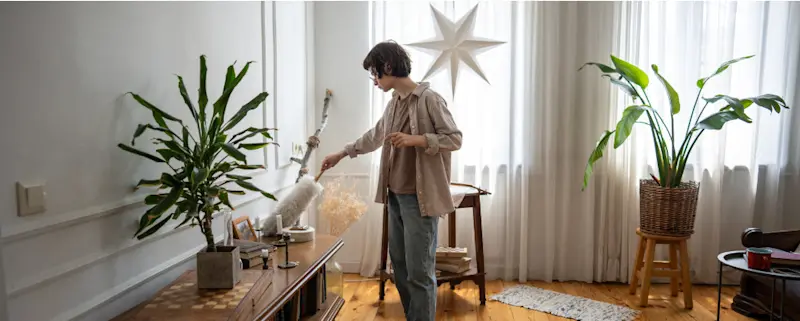 A woman clenaing up seasonal decor from her minimalist apartment