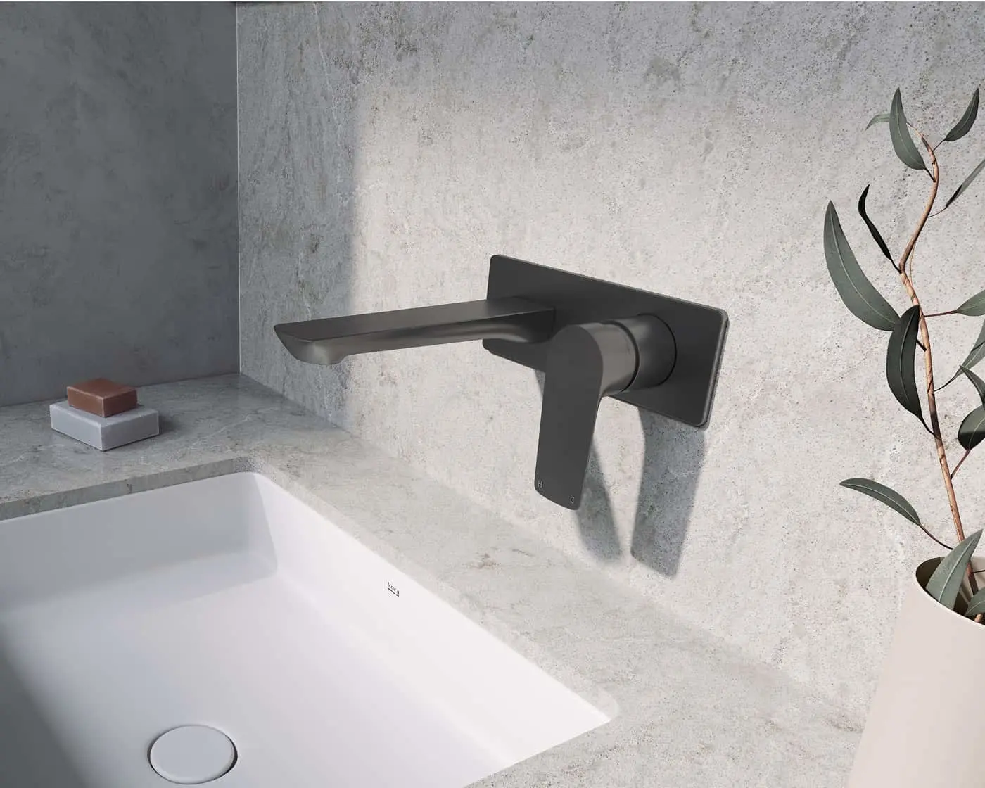 Modern black wall-mounted bathroom faucet above white sink with concrete wall and eucalyptus branch.