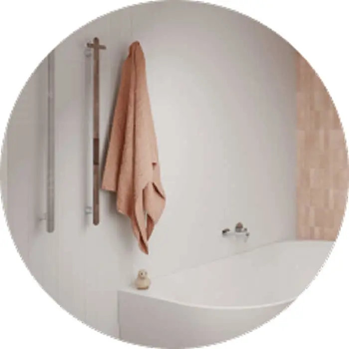 White bathroom with peach towel hanging on wooden wall hooks above a bathtub with a small rubber duck toy