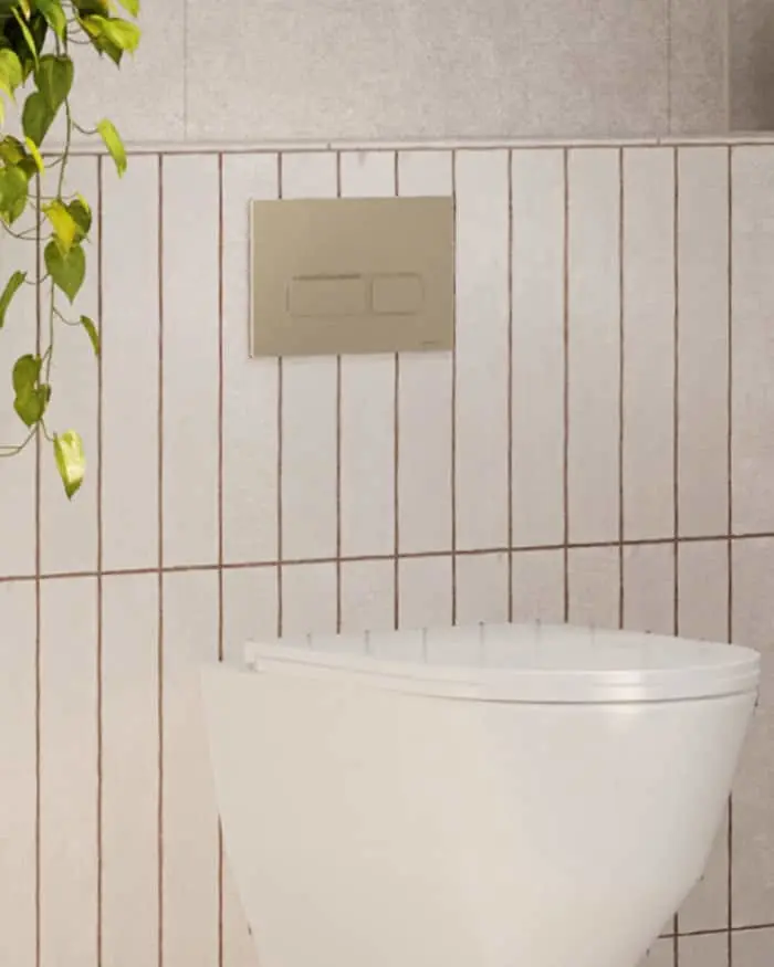 White toilet against white tiled wall with beige grout lines, beige flush plate above, green plant visible on left