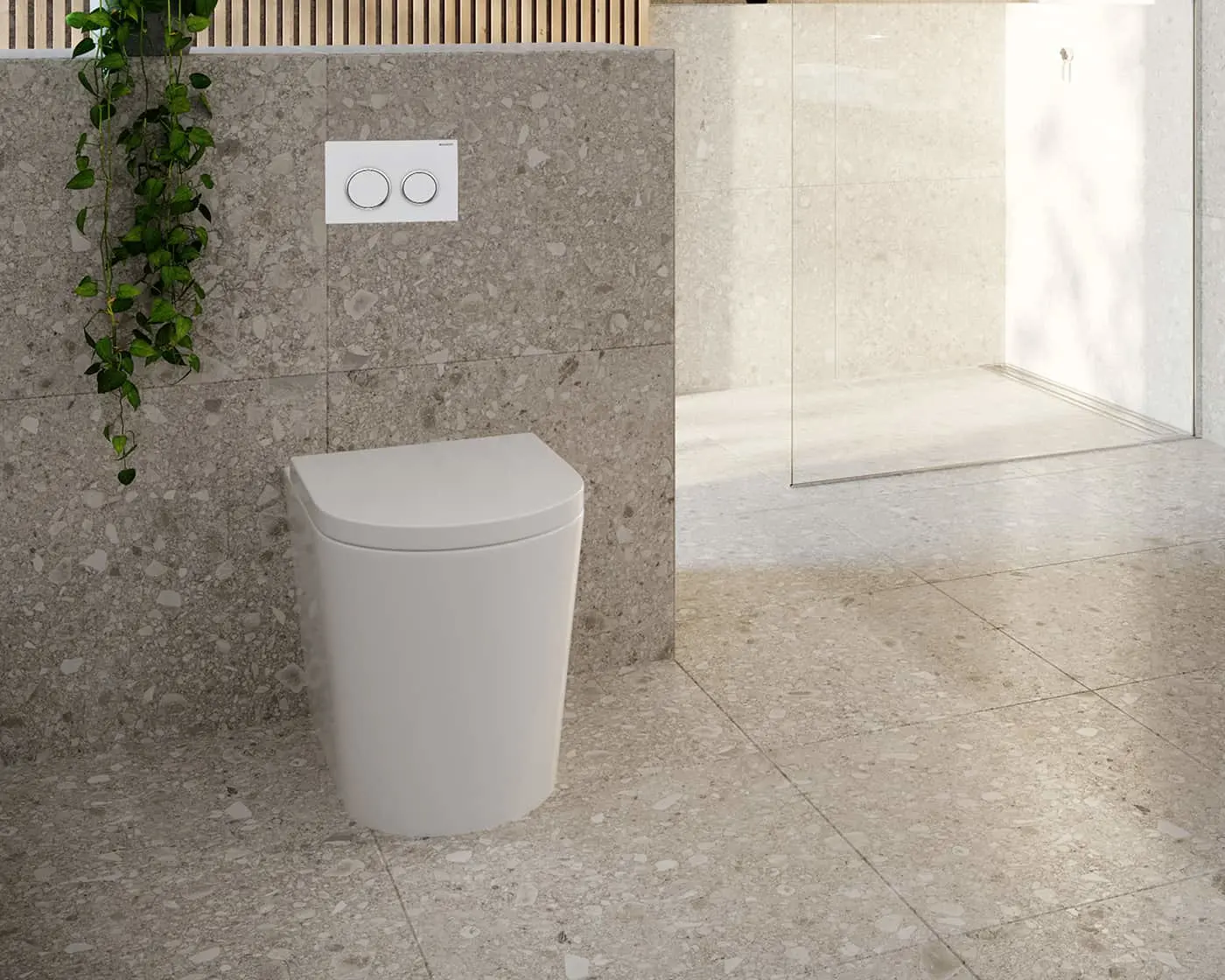 White toilet with dual-button flush plate on gray stone wall, green plant vine, beige tile floor, glass shower enclosure.