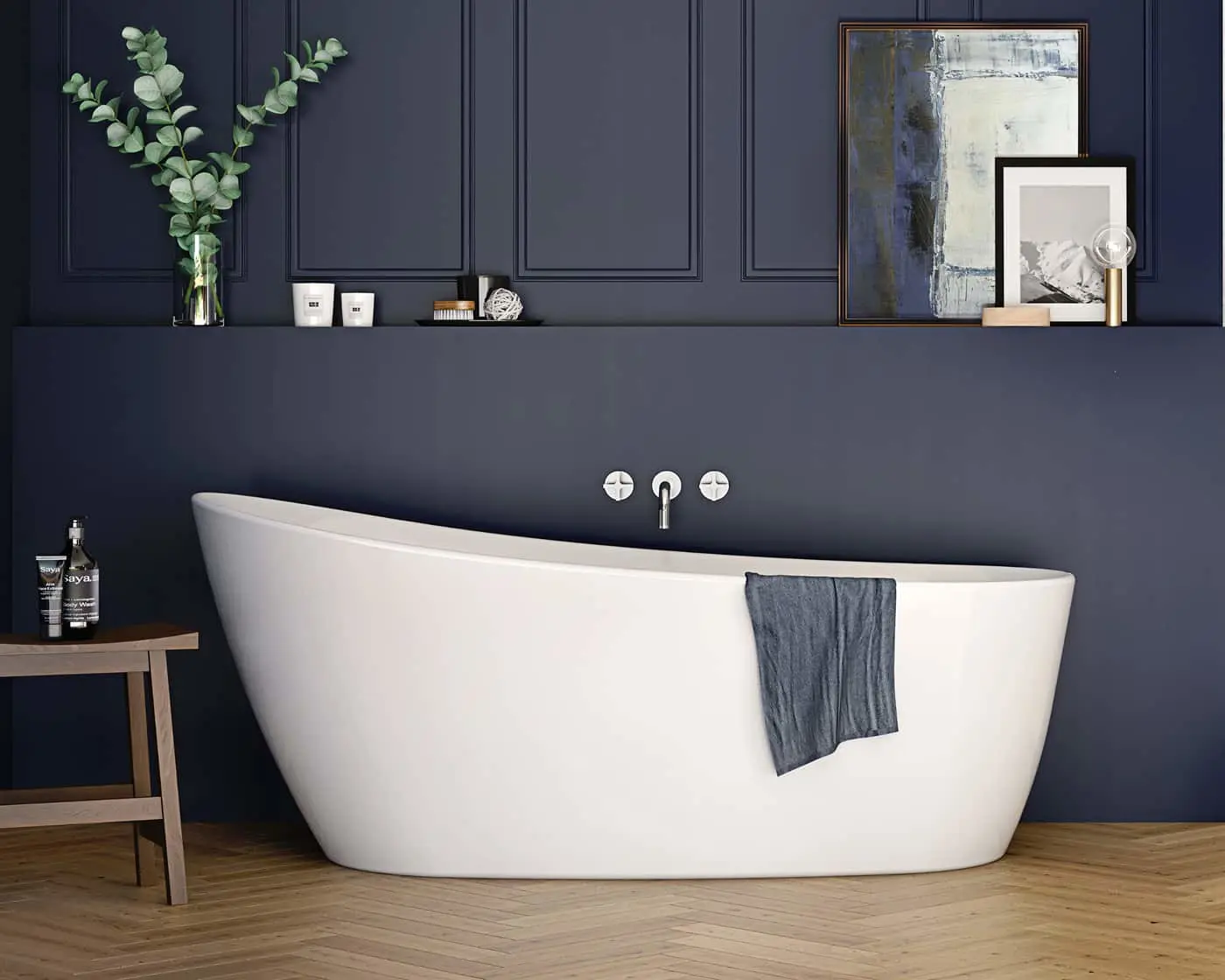 White freestanding bathtub against dark blue paneled wall with framed artwork and eucalyptus branches on shelf above.