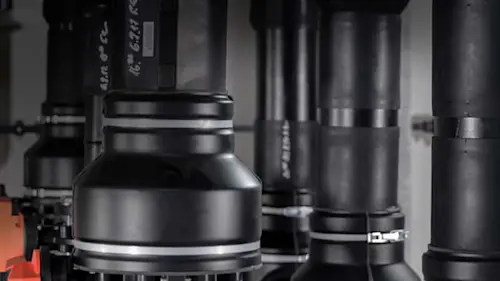 Close-up of black and gray metallic industrial pipe fittings and cylindrical components.