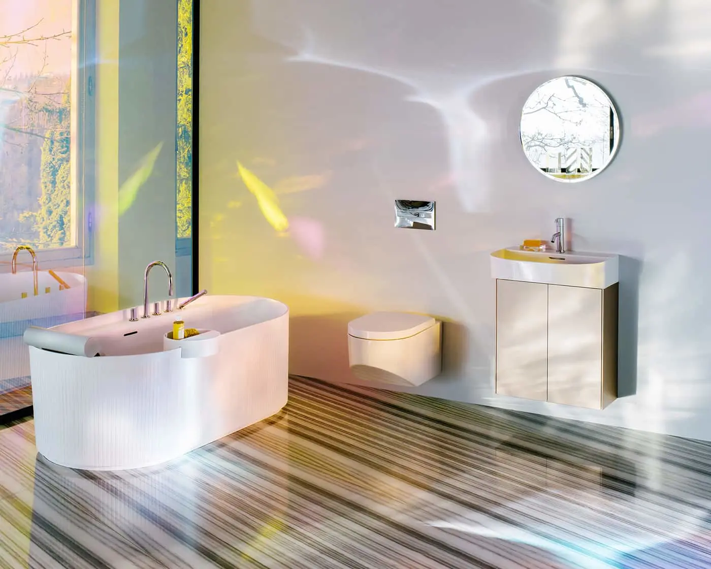Modern bathroom with white freestanding tub, wall-mounted toilet, vanity, and colorful striped flooring.