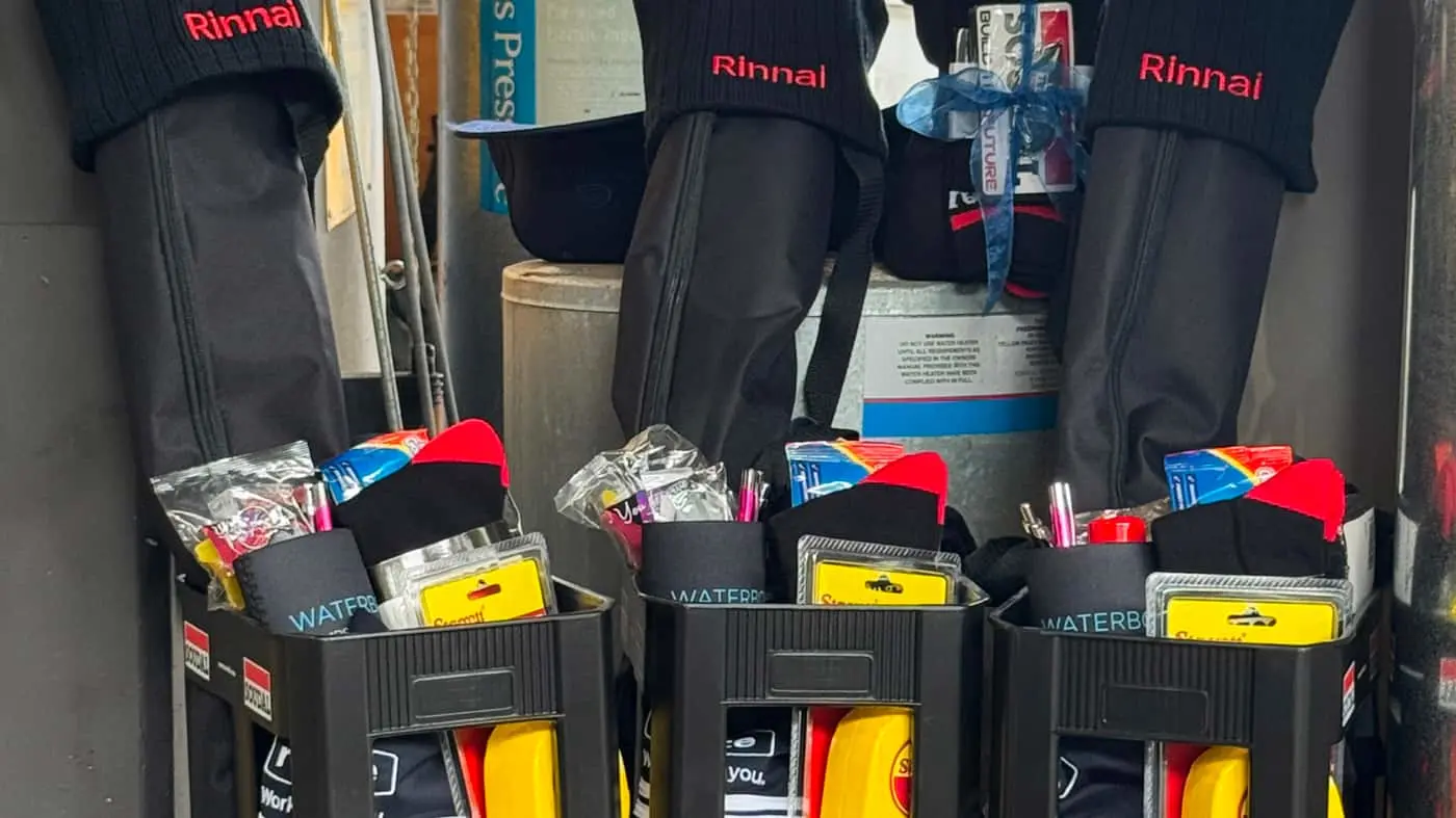 Three black rolling suitcases with Rinnai branding, each containing gift bags and promotional items in front.