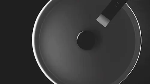 Overhead view of a dark circular sink with a black faucet against a dark background